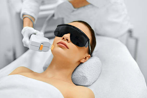 Patient receiving a professional facial laser treatment at a skin care clinic.